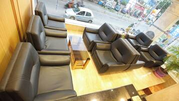Een zithoek met banken en stoelen, een houten bijzettafeltje en uitzicht op de straat.