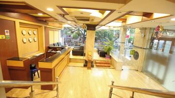 A hotel lobby with a reception desk, seating area, and a decorative pillar.