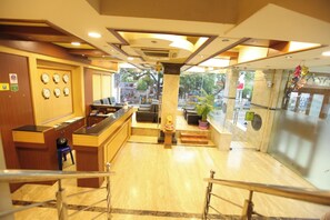 A hotel lobby with a reception desk, seating area, and a decorative pillar.