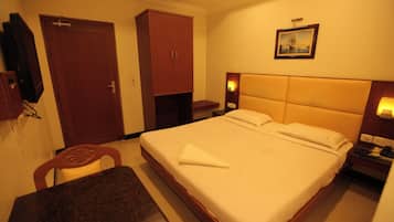 Een hotelkamer met een bed, een bureau, een stoel, een kledingkast en een schilderij aan de muur.