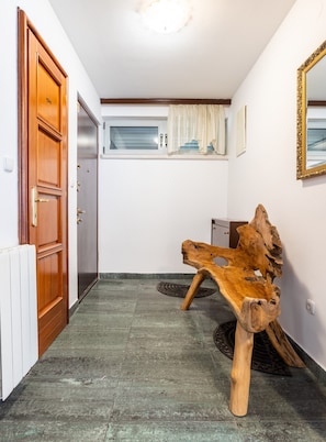 A hallway with a wooden bench, a door, a radiator, a window with curtains, and a mirror on the wall. - Beautiful luxury house with sea view & outside space (Split)