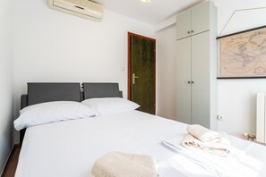 A hotel room with a bed, a wardrobe, a map on the wall, and a towel on the bed. - Beautiful luxury house with sea view & outside space (Split)