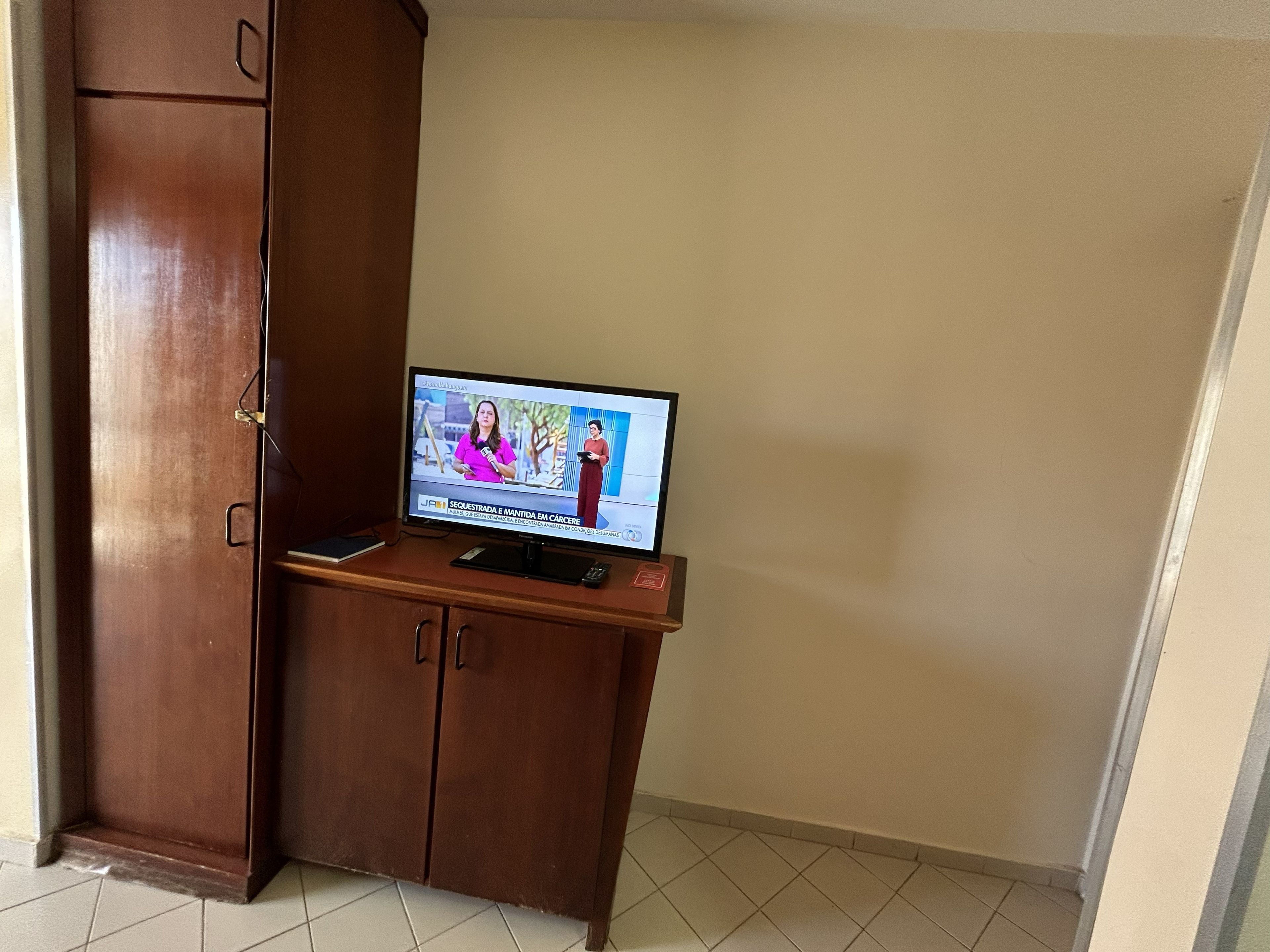 A television on a wooden cabinet in a room with a tiled floor.