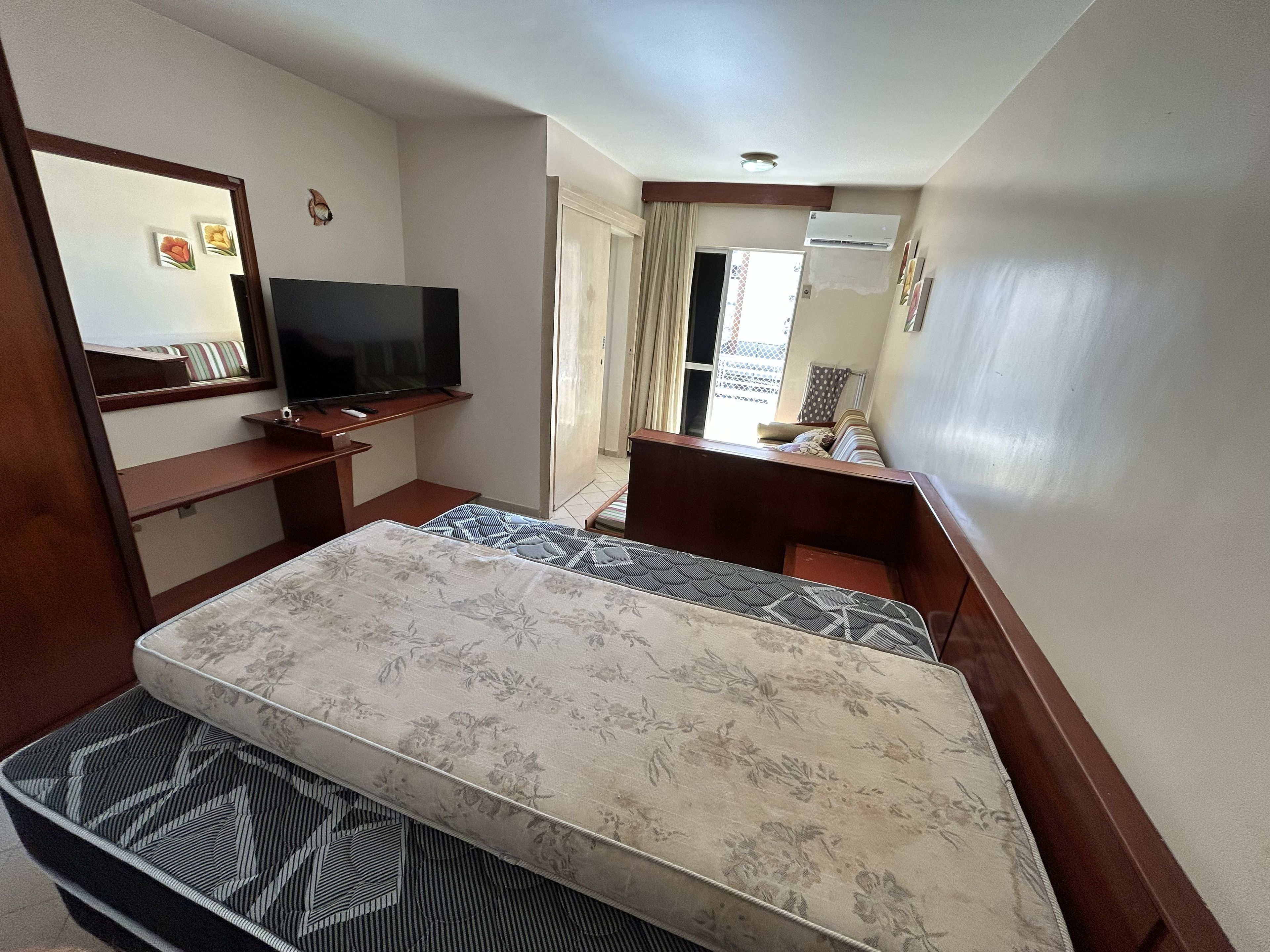 Una habitación de hotel con una cama, televisión, escritorio y ventana.