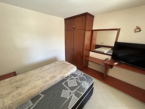 A bedroom with a bed, a wooden wardrobe, a television, and a mirror. - CRCN - Eldorado Flat Service (Caldas Novas)