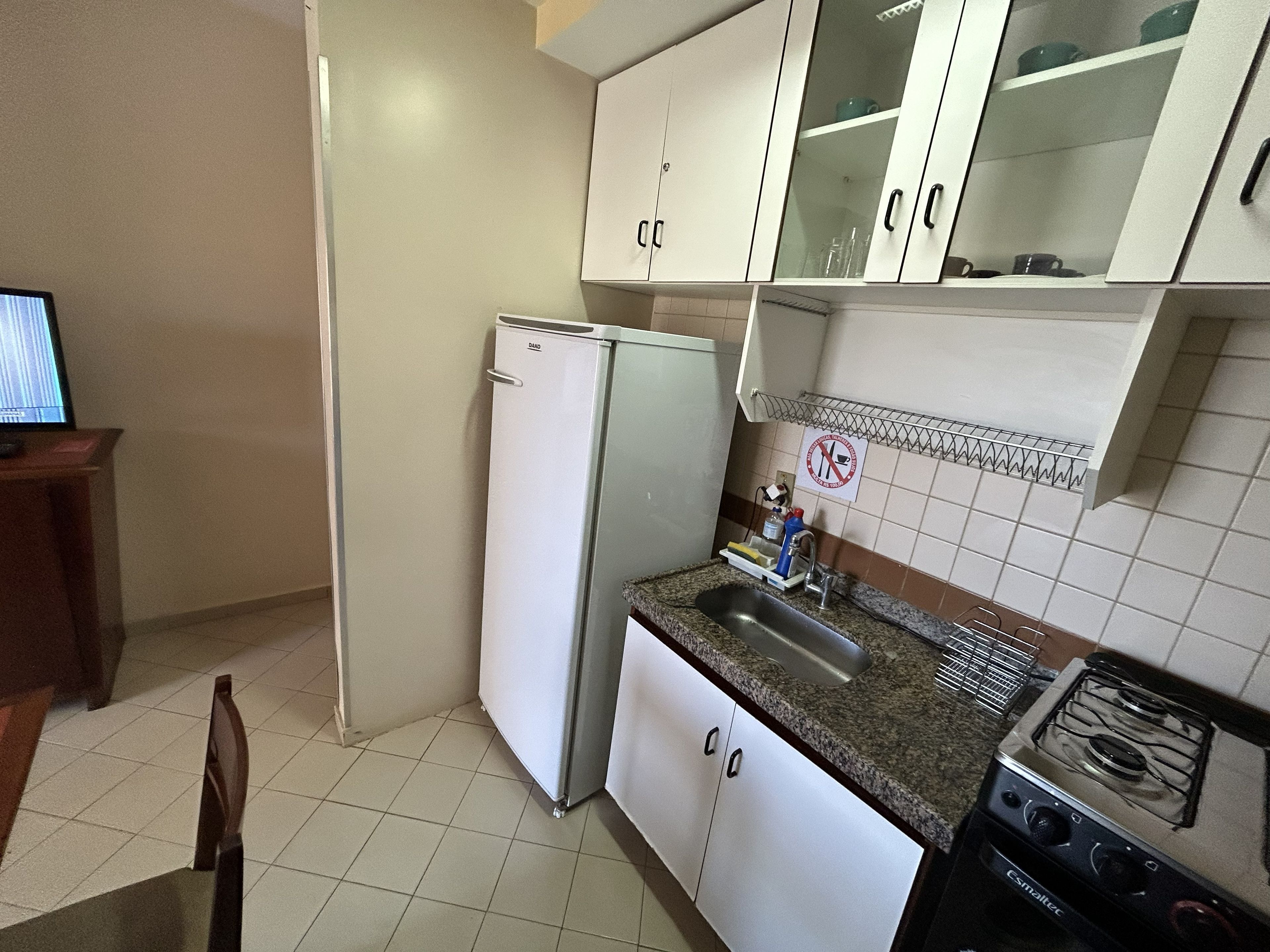 Una cocina con armarios blancos, un fregadero de acero inoxidable, una estufa y un refrigerador.
