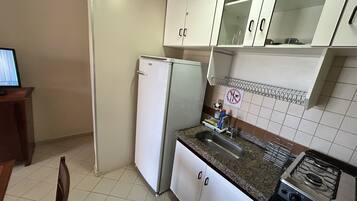 Una cocina con armarios blancos, un fregadero de acero inoxidable, una estufa y un refrigerador.