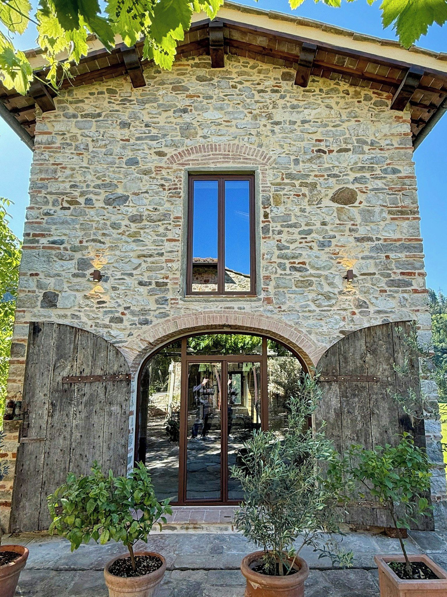 A stone building with a central window and an arched entrance.