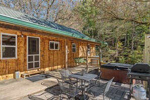 Eine Holzhütte mit Veranda, Sitzgelegenheit im Freien und Grill.