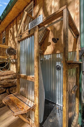 A rustic wooden building with a metal door and a wooden bench outside. - Secluded Cabin with Hot Tub • Outdoor Shower • Private Trail and Pond (Parrottsville)