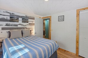 Ein Schlafzimmer mit Bett, Tür und Wand mit Kunstwerken.