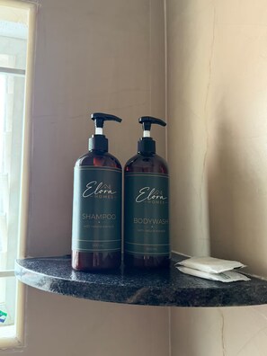 Zwei Flaschen Elora Homes Shampoo und Duschgel auf einer Badezimmerablage.