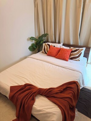 Ein Hotelzimmer mit Bett, Pflanze und einem Vorhangfenster.