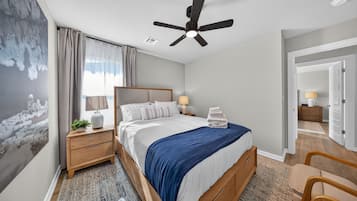A hotel room with a bed, bedside tables, a ceiling fan, and a view of the hallway.