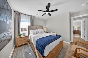 A hotel room with a bed, bedside tables, a ceiling fan, and a view of the hallway. - Refined Luxury | Hot Tub + Gym | Dog friendly | Near Amphitheater (Broken Arrow)