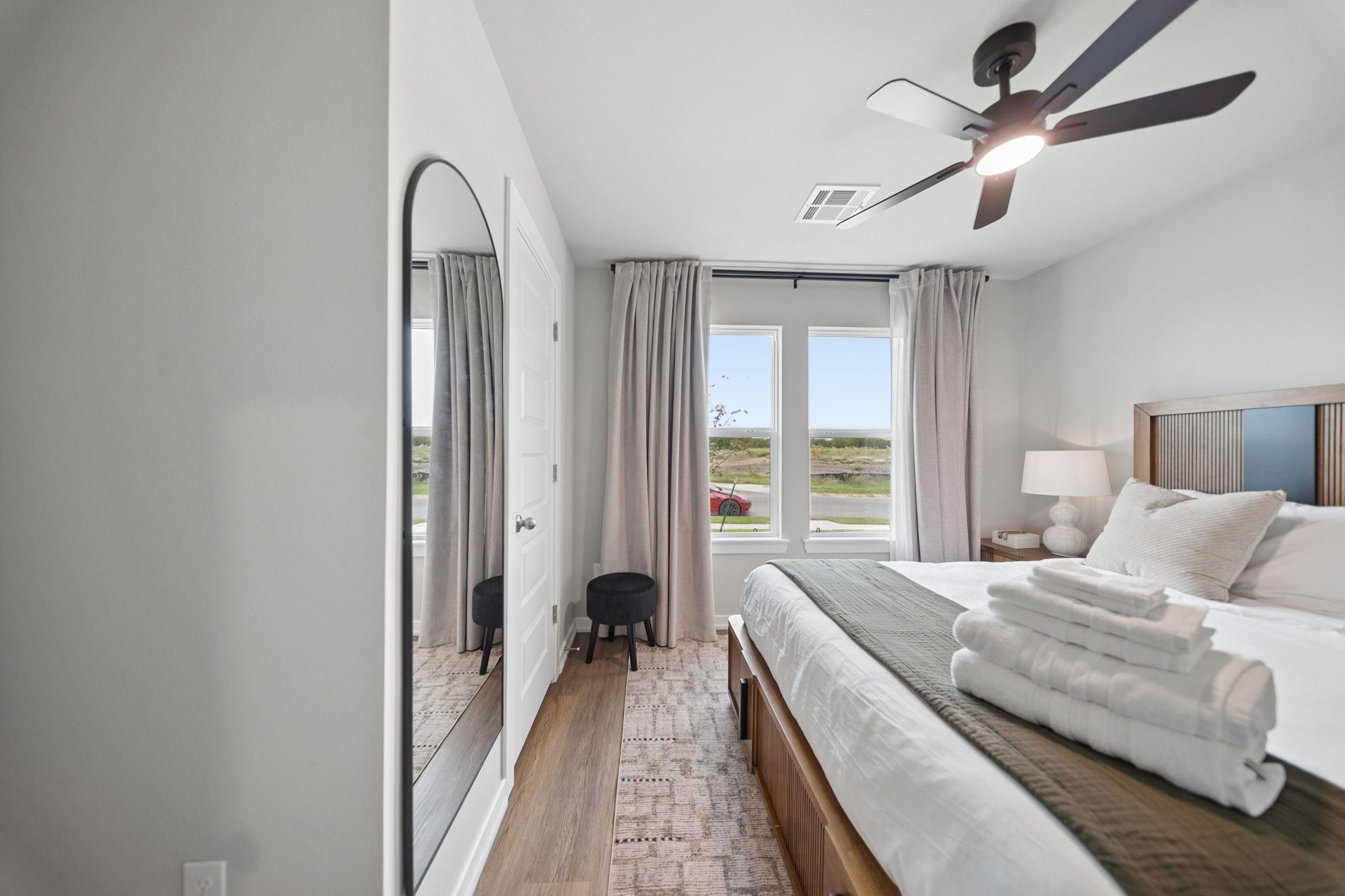 Une chambre d’hôtel avec un lit, une table de chevet, une lampe, un ventilateur de plafond et une vue sur l’extérieur.