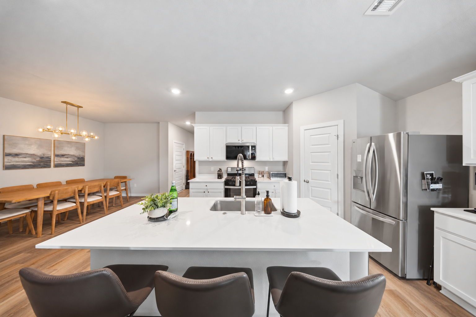 A modern kitchen with white cabinets, stainless steel appliances, and a central island with seating.