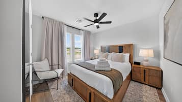 A modern bedroom with a bed, bedside tables, a ceiling fan, and a view of the outdoors.