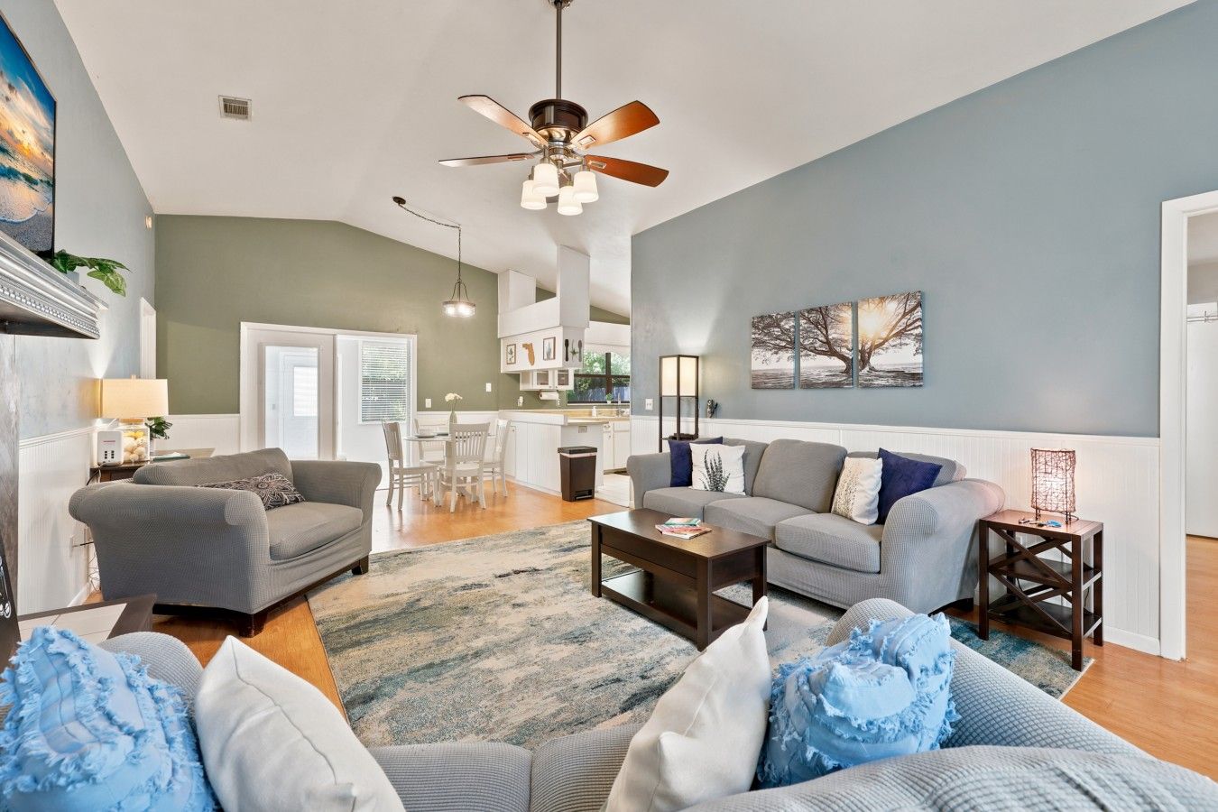 A spacious living room with a sofa, coffee table, and a ceiling fan.