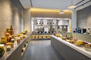 A modern kitchen with a central island, equipped with various appliances and a buffet setup.