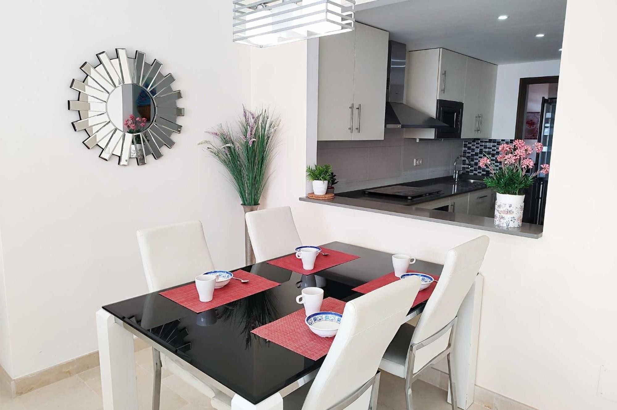 A dining area with a black table, white chairs, and red placemats.