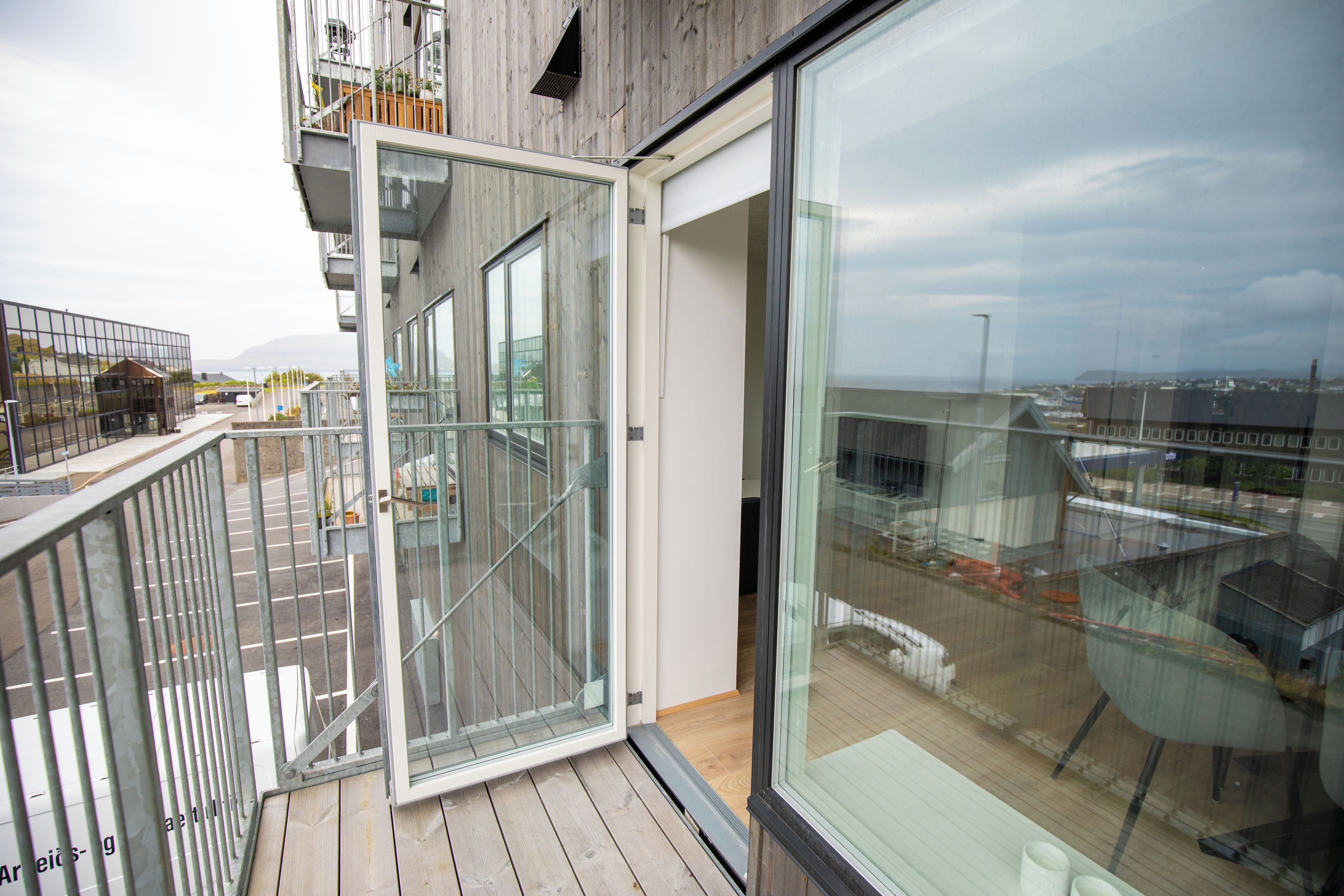 A modern building with a balcony, large windows, and a view of the cityscape.
