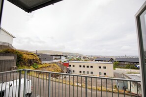 Blick vom Balkon auf eine Stadt mit Gebäuden und einer fernen Landschaft.