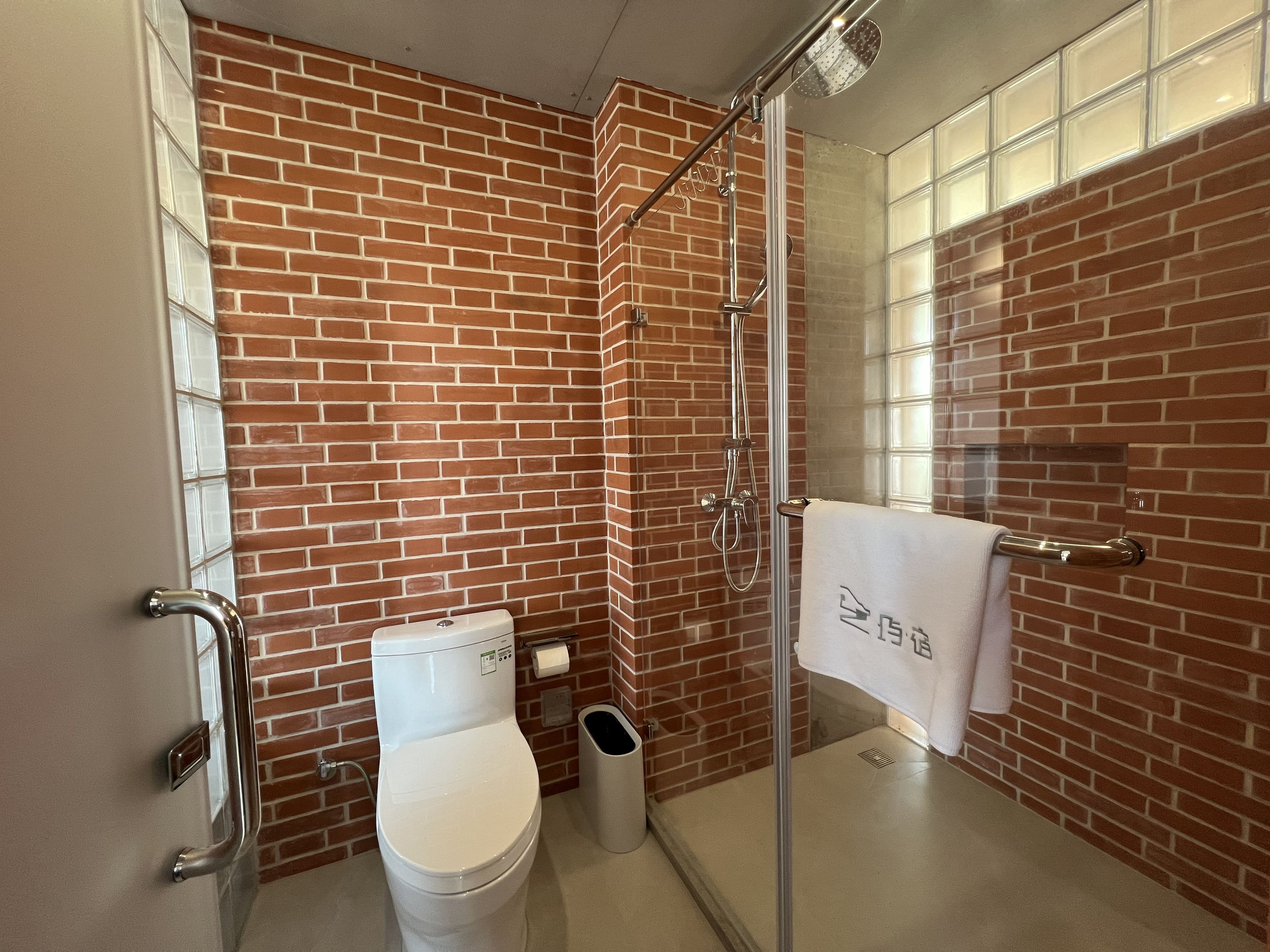 A bathroom with a toilet, a glass shower enclosure, and a towel rack.