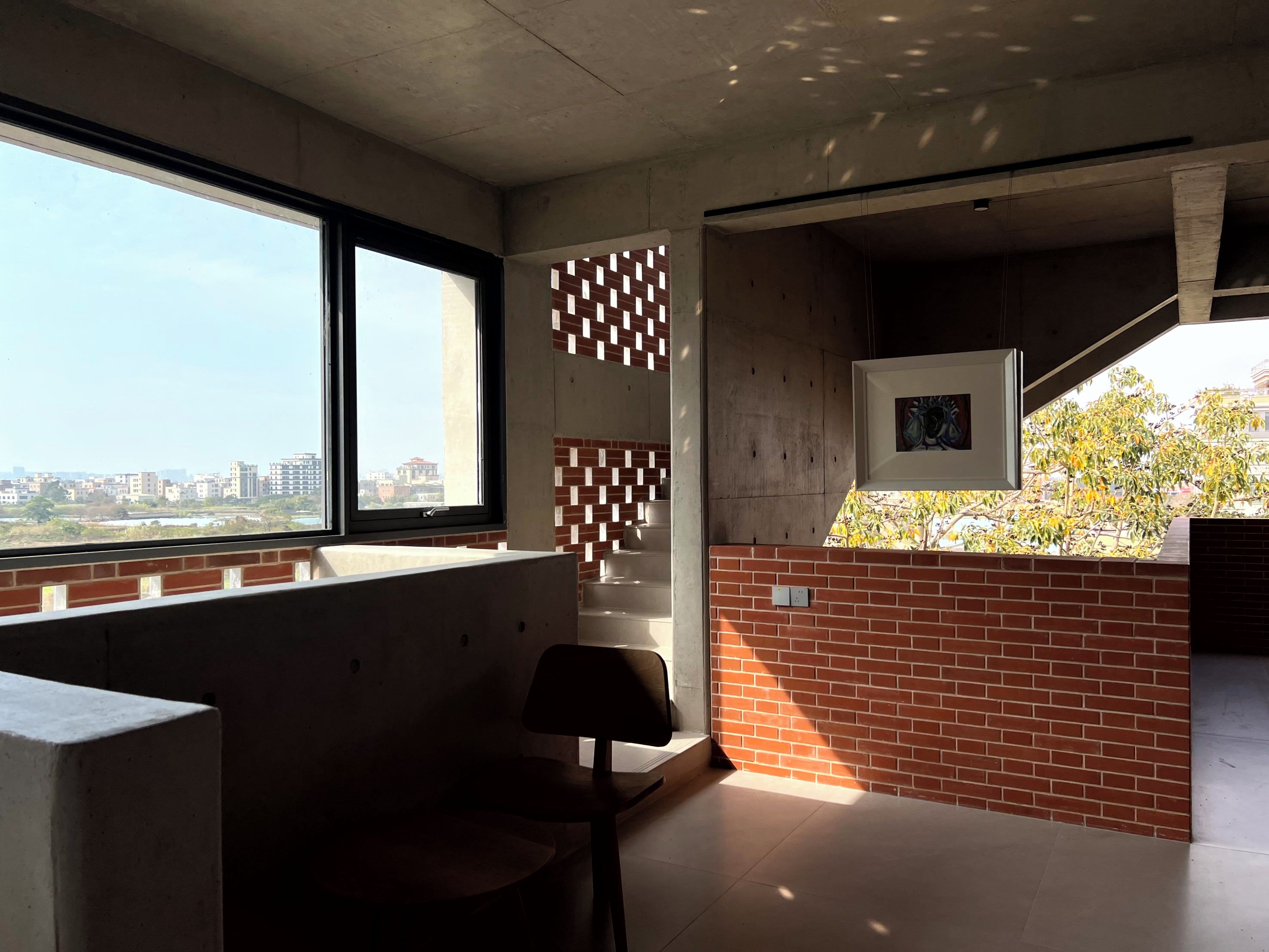 A modern interior with a large window, a brick accent wall, and a framed picture.