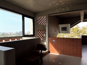 A modern interior with a large window, a brick accent wall, and a framed picture.
