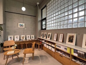 A library with bookshelves, framed artworks, and wooden chairs. - Yu Stay (Shantou)
