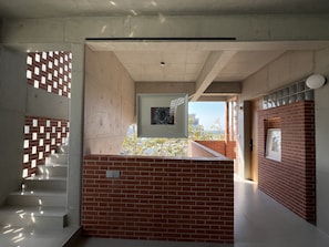 Un couloir avec un mur en briques, une œuvre d’art encadrée et un escalier.