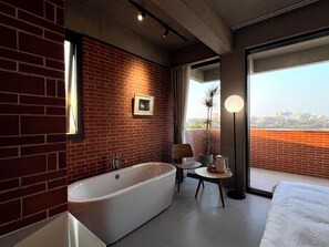 A modern bathroom with a large bathtub, a small table with a kettle, and a view of the city through a large window. - Yu Stay (Shantou)