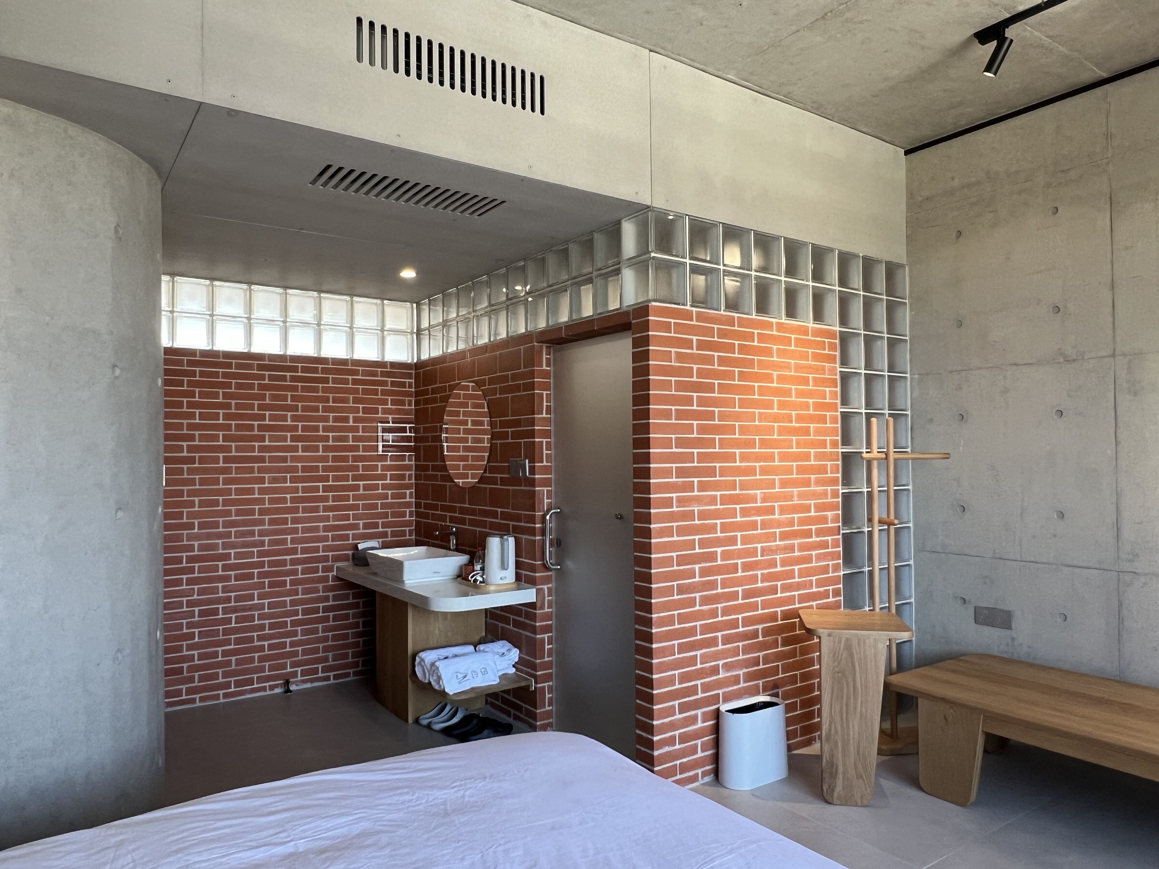 A modern bathroom with a brick wall, a sink, and a bench.
