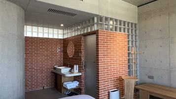 A modern bathroom with a brick wall, a sink, and a bench.