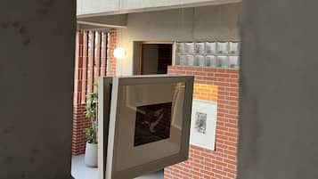 Un interior moderno con vigas de hormigón a la vista, una pared de ladrillo y una obra enmarcada.