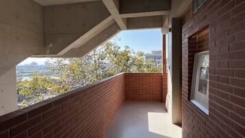 A balcony with a view of a river and trees, a tiled floor, and a brick wall.