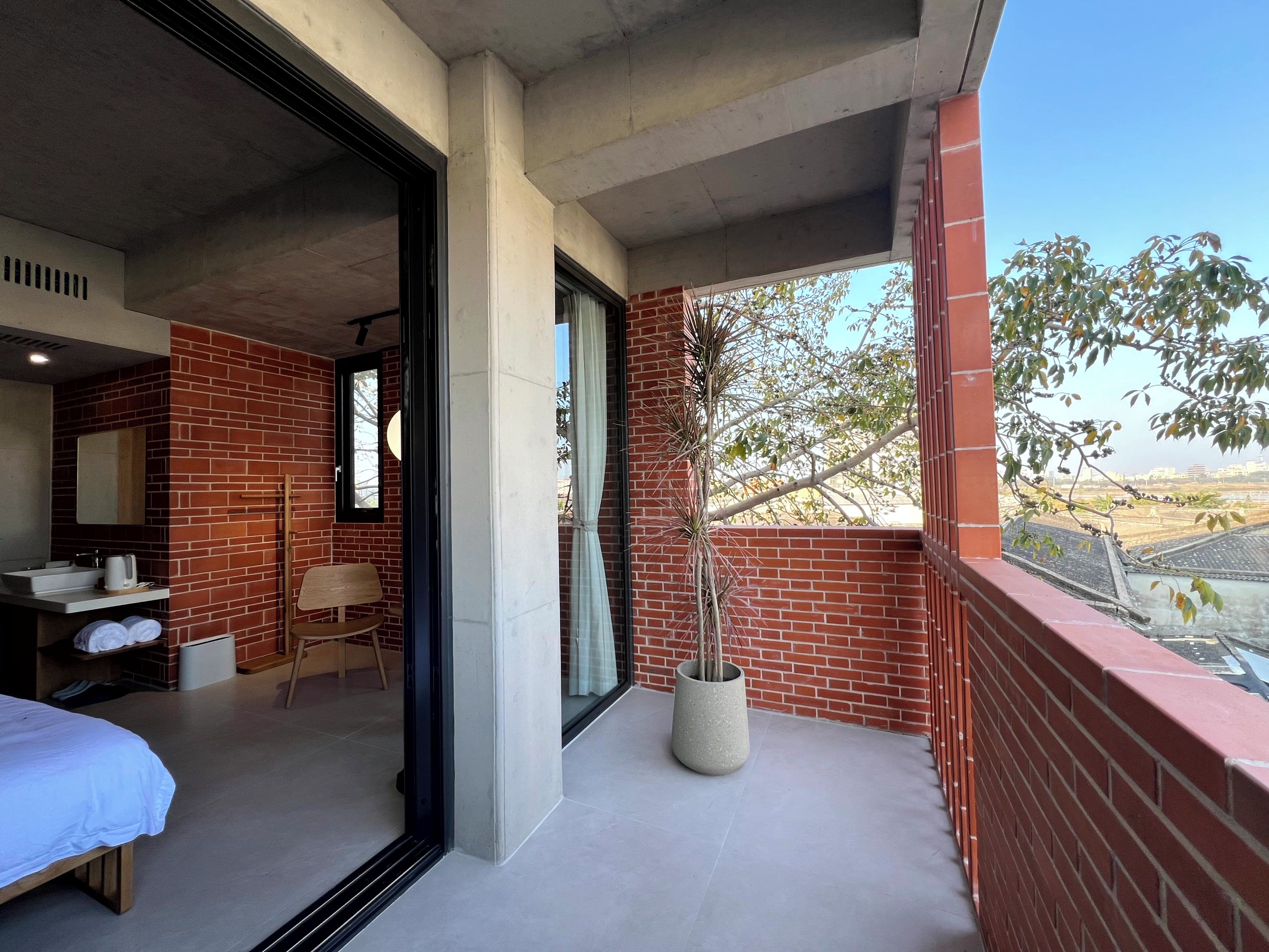 A hotel room with a balcony, a bed, a seating area, and a view of the landscape.