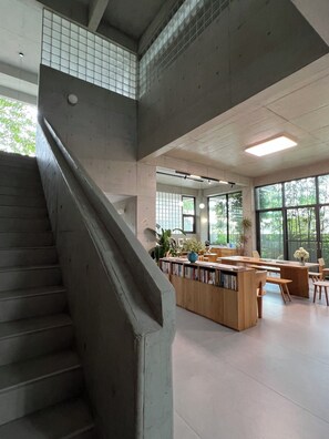 A modern library with a central reading area, bookshelves, and a staircase.