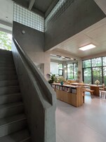 A modern library with a central reading area, bookshelves, and a staircase.