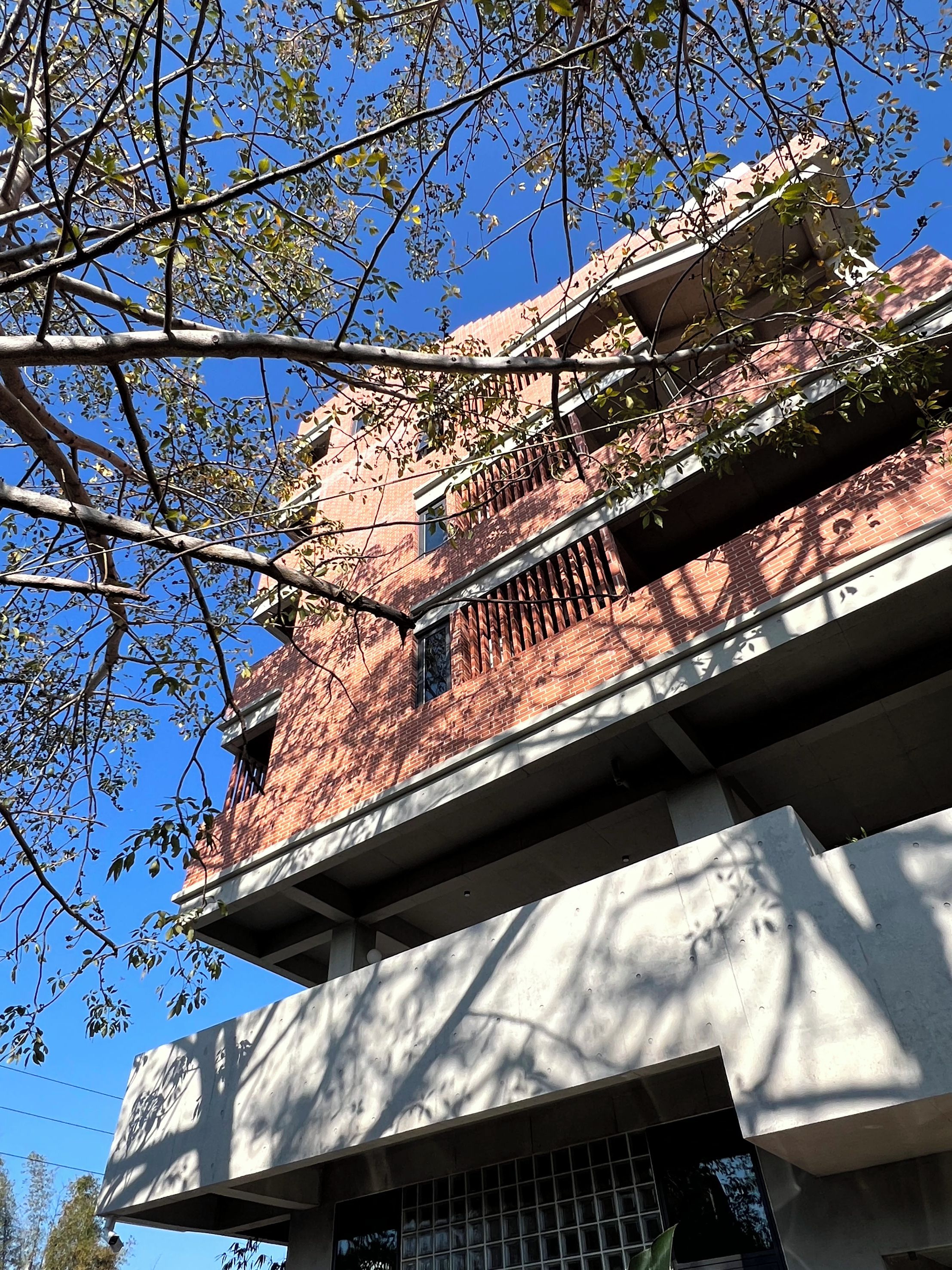 Un edificio con fachada de ladrillo, una ventana visible y un balcón.