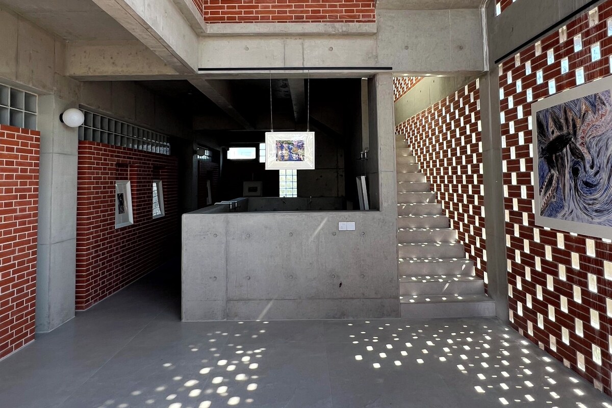 Un interior moderno con una escalera central, paredes de ladrillo y luminarias de techo con diseños.