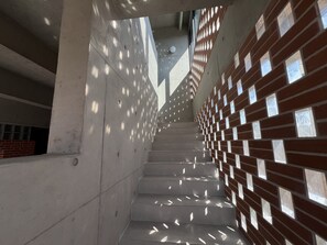 Una escalera de diseño moderno, con una pared de ladrillo con recortes cuadrados a la derecha y una pared de hormigón liso a la izquierda.