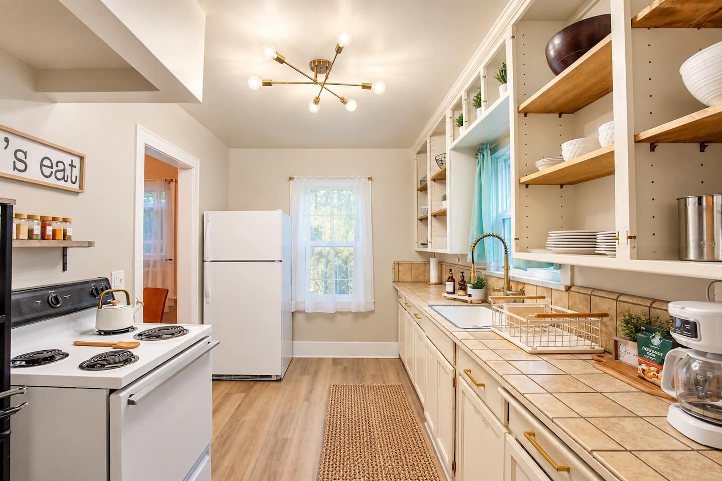 Una cocina con estufa, refrigerador y una lámpara colgante.