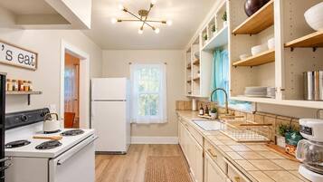 Una cocina con estufa, refrigerador y una lámpara colgante.