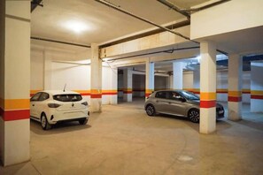 Eine Parkgarage mit Betonpfeilern und einem weißen Auto im Vordergrund.