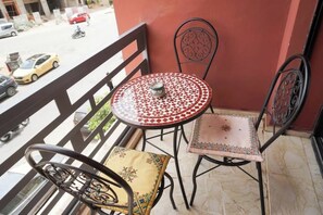 Ein Balkon mit einem runden Tisch und zwei Stühlen, einer davon mit Sitzkissen.