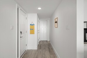A hallway with white walls, a wooden floor, and a door at the end. - Renovated Direct Oceanfront Island Club (Hilton Head)