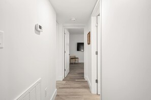 A hallway with white walls, a wooden floor, and a chair in the distance. - Renovated Direct Oceanfront Island Club (Hilton Head)