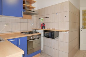 Una cocina compacta con estufa a gas, horno, microondas y armarios azules.